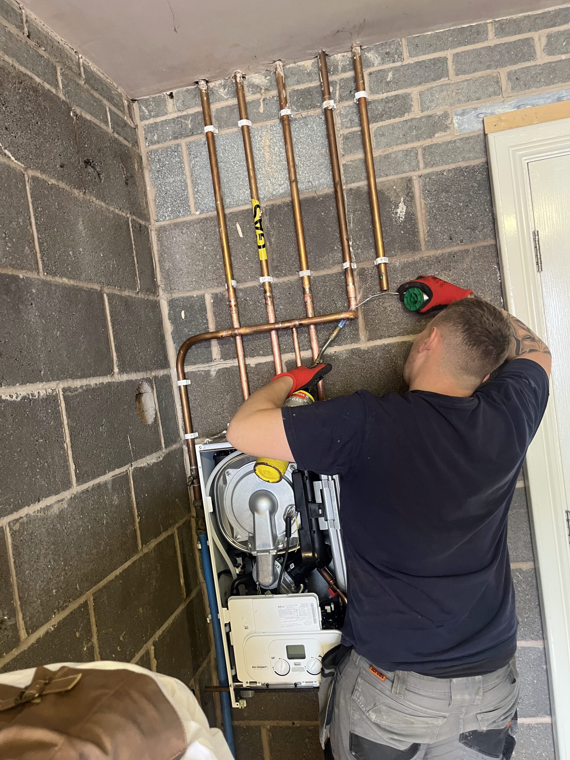 A Cheshire Boilers engineer fitting a boiler and copper pipework